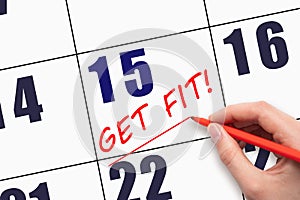 15th day of the month. Hand writing text GET FIT and drawing a line on calendar date. Save the date.