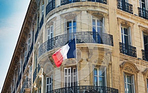 16 Aug 2018. Raised french flag at old concrete residential complex building in Marseille France.