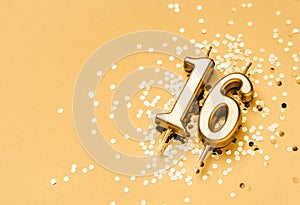 16 years celebration festive background made with golden candle in the form of number Sixteen lying on sparkles