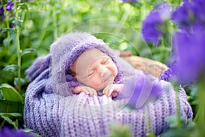 17 day old Smiling newborn baby is sleeping on his stomach in the basket on nature in the garden outdoor