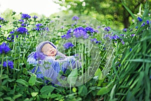 17 day old Smiling newborn baby is sleeping on his stomach in the basket on nature in the garden outdoor.