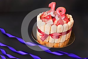 18 birthday party. strawberry tiramisu cake on black background with ribbon. Focus on strawberries.