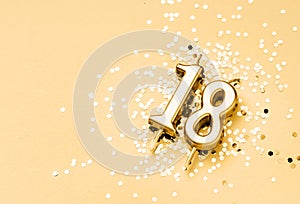 18 years birthday celebration festive background made with golden candle in the form of number Eighteen lying on sparkles