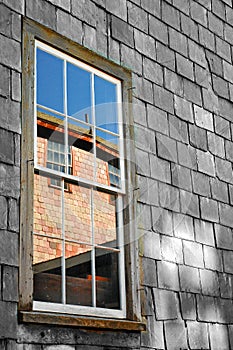 1890s slate sided factory wall with window and clear reflection