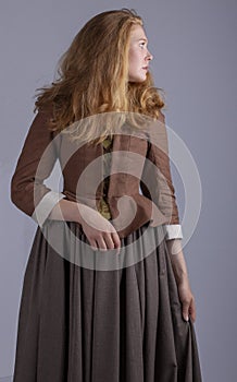 18th century woman in brown outfit on plain studio backdrop