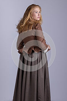 18th century woman in brown outfit on plain studio backdrop