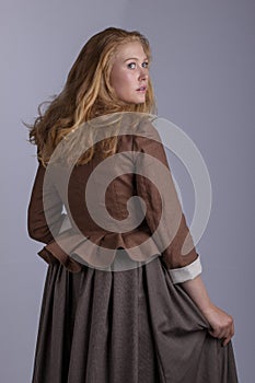 18th century woman in brown outfit on plain studio backdrop