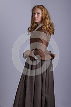 18th century woman in brown outfit on plain studio backdrop