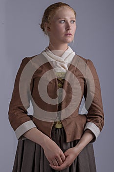 18th century woman in brown outfit on plain studio backdrop