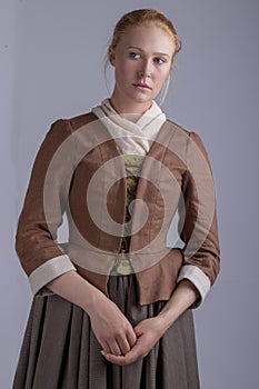 18th century woman in brown outfit on plain studio backdrop