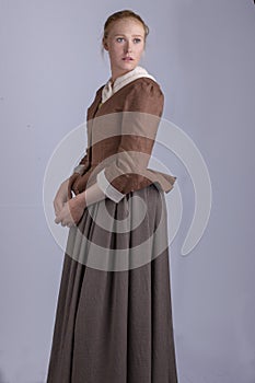 18th century woman in brown outfit on plain studio backdrop