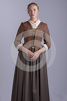 18th century woman in brown outfit on plain studio backdrop