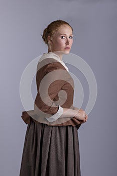 18th century woman in brown outfit on plain studio backdrop