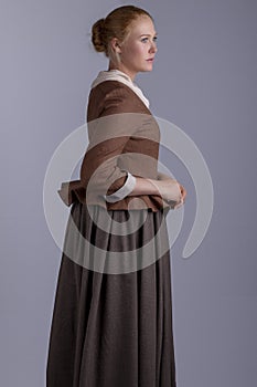 18th century woman in brown outfit on plain studio backdrop