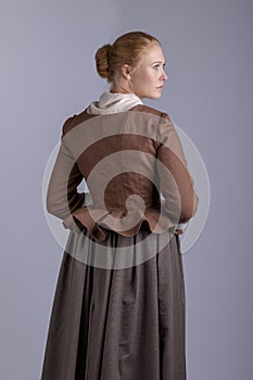 18th century woman in brown outfit on plain studio backdrop