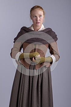 18th century woman in brown outfit on plain studio backdrop