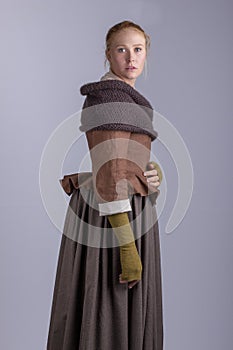 18th century woman in brown outfit on plain studio backdrop