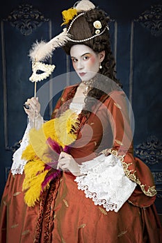 An 18th-Century woman wearing an a la Francaise gown holding a mask