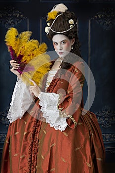 An 18th-Century woman wearing a robe a la Francaise and holding a feather fan