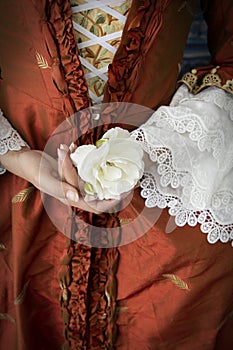 An 18th-Century woman wearing a robe a la Francaise and holding a white rose