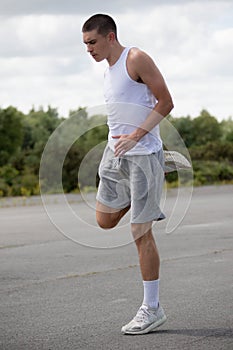 A 19 Year Old Teenage Boy Stretching In A Public Park