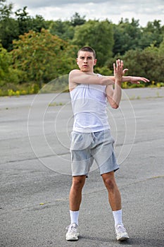 A 19 Year Old Teenage Boy Stretching In A Public Park