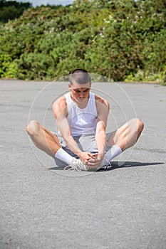 A 19 Year Old Teenage Boy Stretching In A Public Park