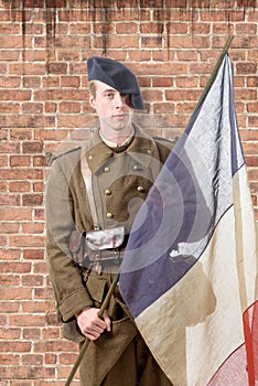 1940 french soldier with a flag, wall of red brick at the back