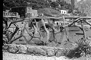 1964, Italy, Capri - Beyond the fence dozens of vacationers bathe in the sea of Marina Piccola