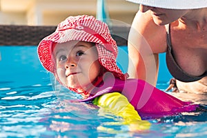 2-3 years old child with mother in swimming pool learn to swim. Summer at home concept