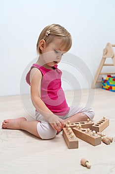 A 2.5 year old child sorts shapes of different sizes. Wood childrens game by Montessori system.