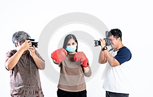 2 Asian man photographers taking pictures of woman Wearing a surgical masks Doing exercise with boxing