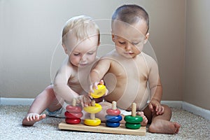 2 babies playing with toys inside