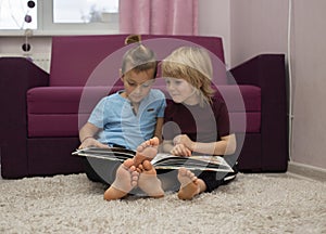 2 barefoot preschool boys are looking at and reading a book together