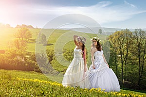 2 beautiful bride on a meadow in the early morning