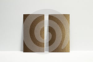 2 blank bronze business cards locked on white wall, 3.5 x 2 inches size as template for design presentation, showcase etc