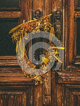 2 brass statues and a wreath of dried flowers on an old wooden door