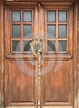 2 brass statues and a wreath of dried flowers on an old wooden door