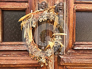 2 brass statues and a wreath of dried flowers on an old wooden door