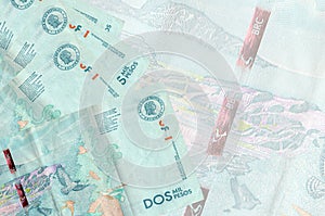 2 Colombian pesos bills lies in stack on background of big semi-transparent banknote. Abstract business background