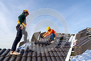 2 Construction workers install new roof at construction site, Electric drill used on new roofs with Concrete Roof Tiles. Concept