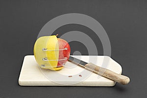 2 different apple halves are held together with three safety pins