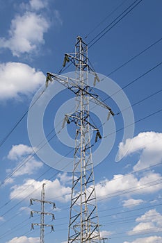 2 electricity power poles and white clouds on blue sky. Energy supply
