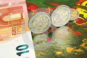 2 euro coins standing on edge, next to 10 euro banknote