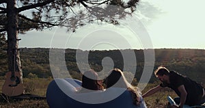 2 girls are taking pictures of a boy in nature.