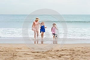 2 girls walking on beach with mom and dog. Happy family walking.