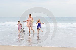 2 girls walking on beach with mom and dog. Happy family walking.