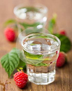 2 glasses of raspberry schnapps with raspberries on wooden board