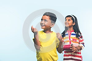 2 indian kids flying kite, one holding spindal or chakri