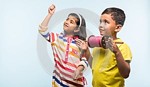 2 indian kids flying kite, one holding spindal or chakri